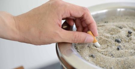 Une personne écrase un mégot de cigarette dans un cendrier, mois sans tabac