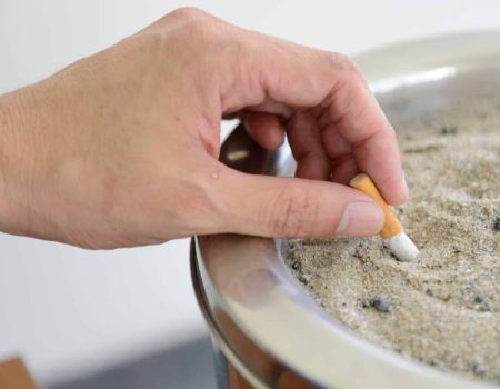 Une personne écrase un mégot de cigarette dans un cendrier, mois sans tabac