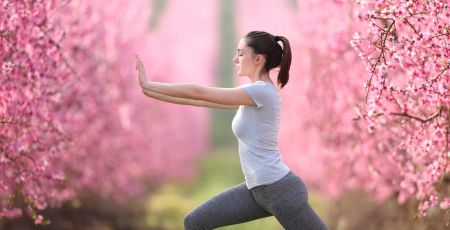 Woman doing tai chi exercise in a pink flowered field