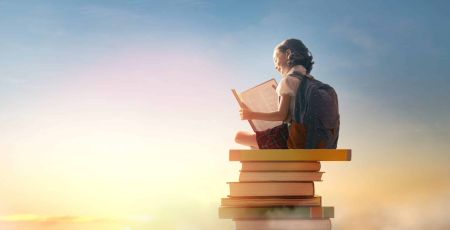 ENFANT QUI LIT SUR UNE TOUR DE LIVRE