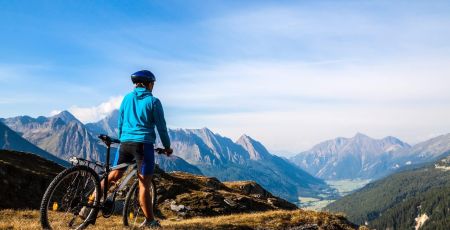Une aventure de 8000kms à vélo pour la protection des forêts Une personne de dos est à vélo face à la montagne.