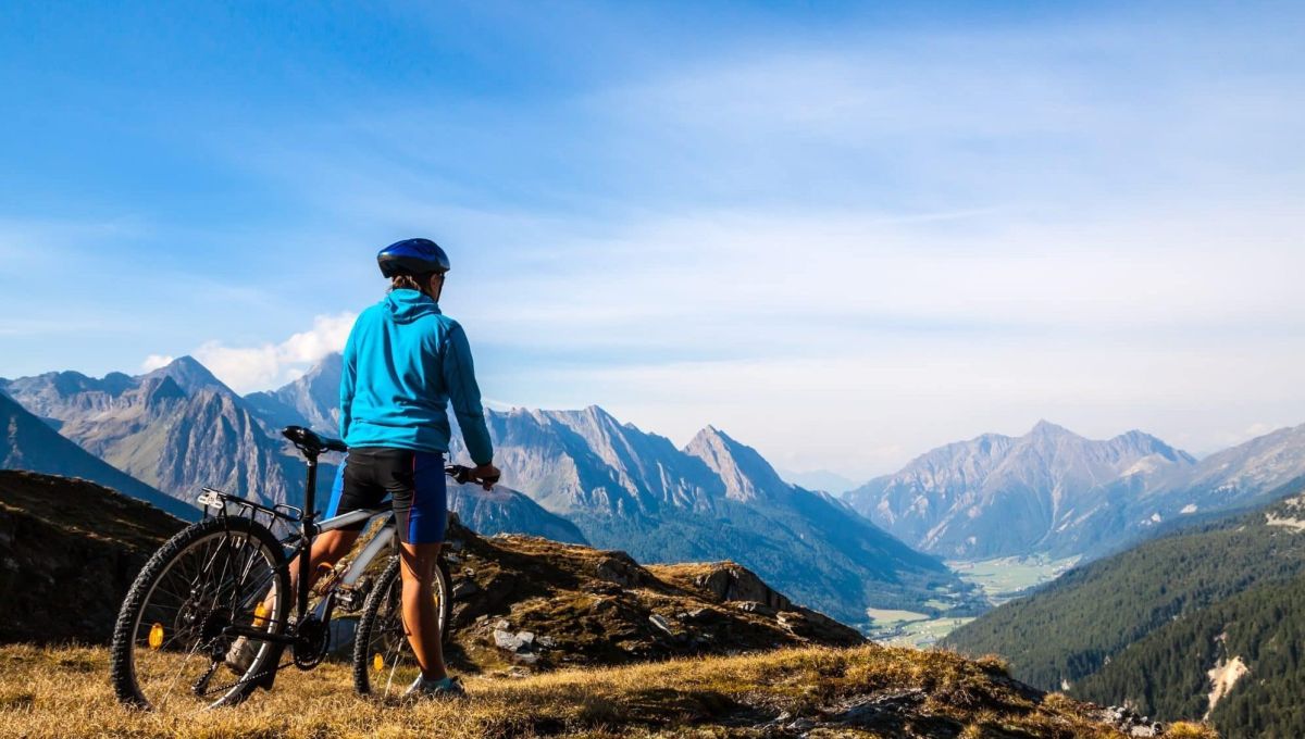 Une aventure de 8000kms à vélo pour la protection des forêts Une personne de dos est à vélo face à la montagne.