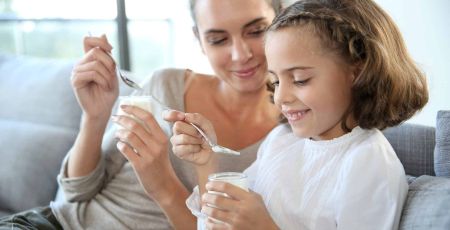 une mère et sa fille mangent un yaourt