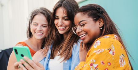 Trois adolescentes avec un téléphone.