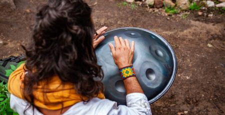 femme de dos qui joue du hand pan dans la nature