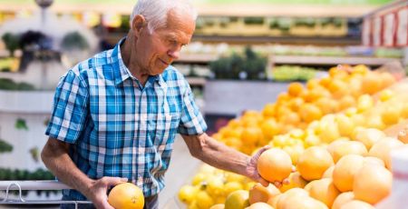 Un homme choisit son pamplemousse dans un supermarché.