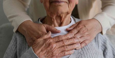 Une personne dont on ne voit pas le visage fait une accolade à une personne agée