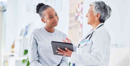 Une femme est assise sur une table d'examen devant elle il y a une femme médecin