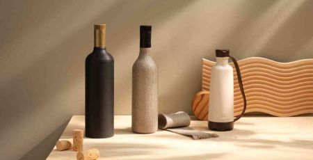 Il y a une bouteille de vin en carton qui est de couleur sombre et le bouchon est doré. A côté une autre bouteille de vin à base de fibres de lin tressées, puis il y a une gourde en résin de bois.
