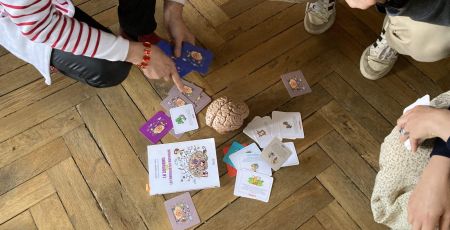 Les cartes de jeu l'attrape temps sont étalés au sol près d'un cerveau en plastique