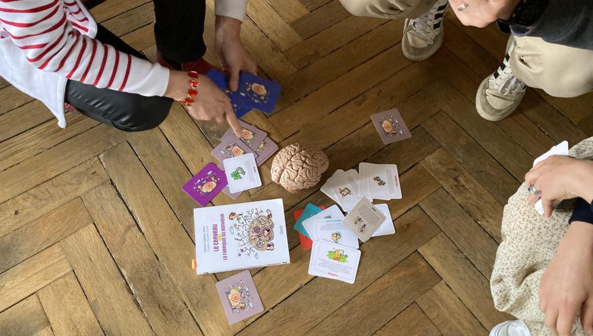 Les cartes de jeu l'attrape temps sont étalés au sol près d'un cerveau en plastique