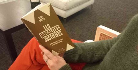 Livre : “Les inégalités justifiées”. Une personne est assise sur une chaise elle tient le livre de Marie Donzel