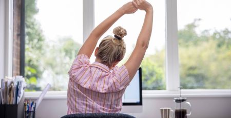 femme de dos s'étire devant PC