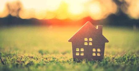 Façade d'une petite maison en carton posée sur l'herbe