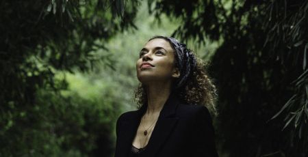 L'artiste Annie Lalalove en pleine nature regarde avec un sourire vers le ciel
