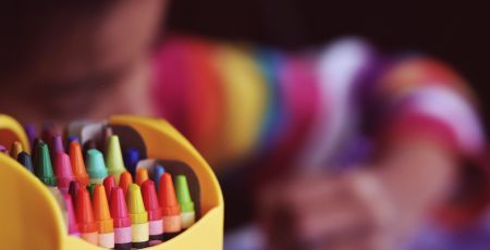 Des crayons de couleurs en premier plan en deuxième planun enfant dessine