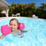 Enfant dans la piscine avec brassards - crédit photo : goodluz via Adobe Stock