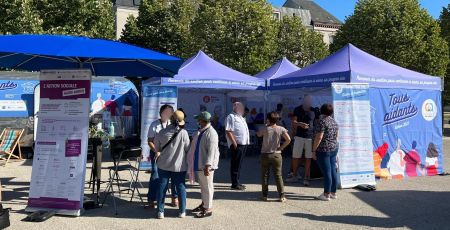 Le stand de la caravane "Tous Aidants", qui est bleu. Il y a du monde devant.