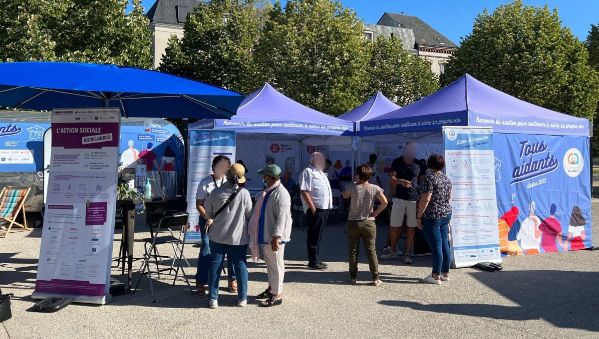 Le stand de la caravane "Tous Aidants", qui est bleu. Il y a du monde devant.