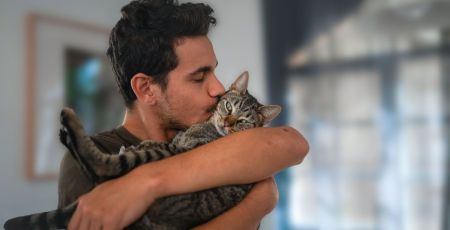 Homme et chat dans ses bras, il lui fait un bisous