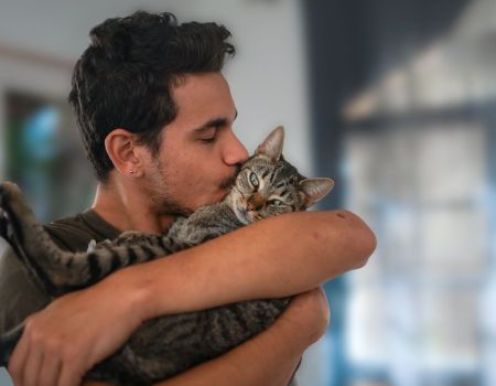 Homme et chat dans ses bras, il lui fait un bisous