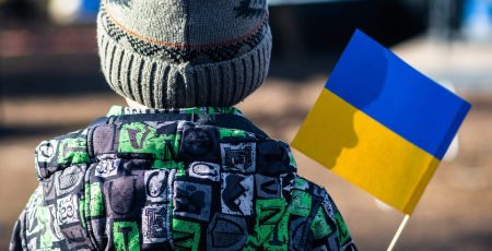 Child or kid with winter clothes, hat and Ukrainian flag, profile of the child is on the flag. War in Ukraine, refugee, refugees concept