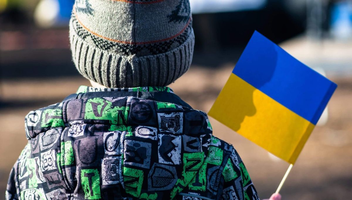 Child or kid with winter clothes, hat and Ukrainian flag, profile of the child is on the flag. War in Ukraine, refugee, refugees concept