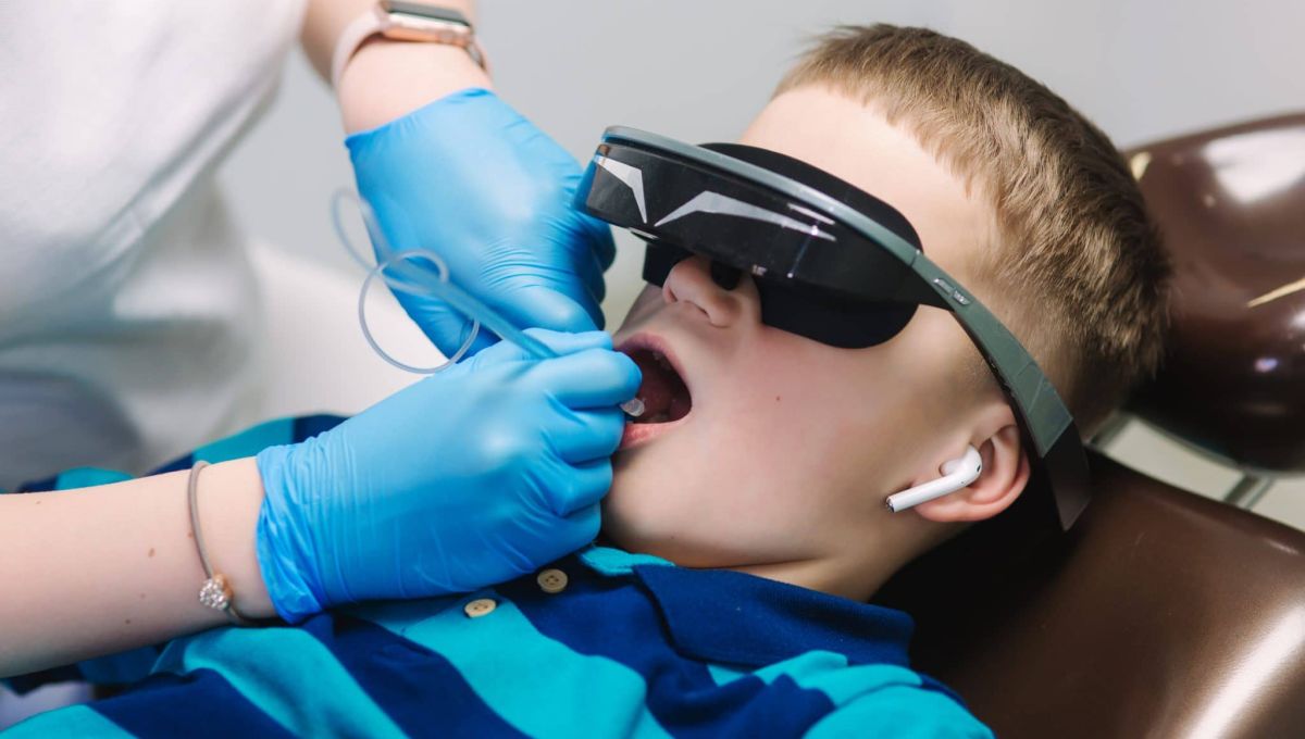 Close up of little boy sitting in dentist in vr glasses and wireless headphones while dentist make x-ray of teeth