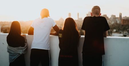 Quatre jeunes sont adossés à un muret ils regardent l'horizon