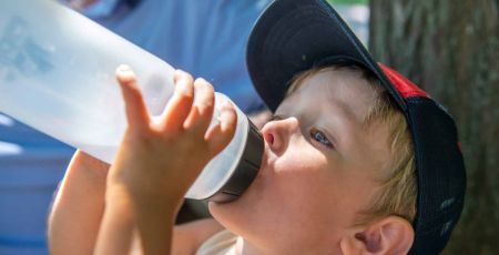 enfant buvant avec une gourde