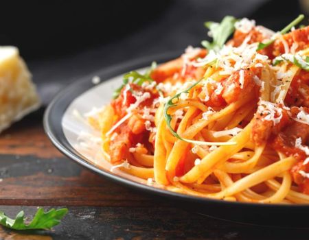Assiette de pâtes à la sauce tomate avec un morceau de parmesan à côté