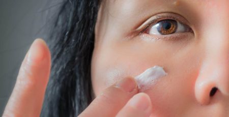 femme s'appliquant de la crème sur le visage
