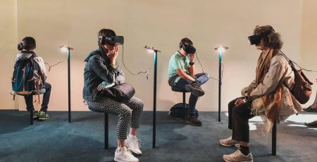 Quatre personnes assisent portent un casque de réalité virtuelle dans ce qui semble être un musée.