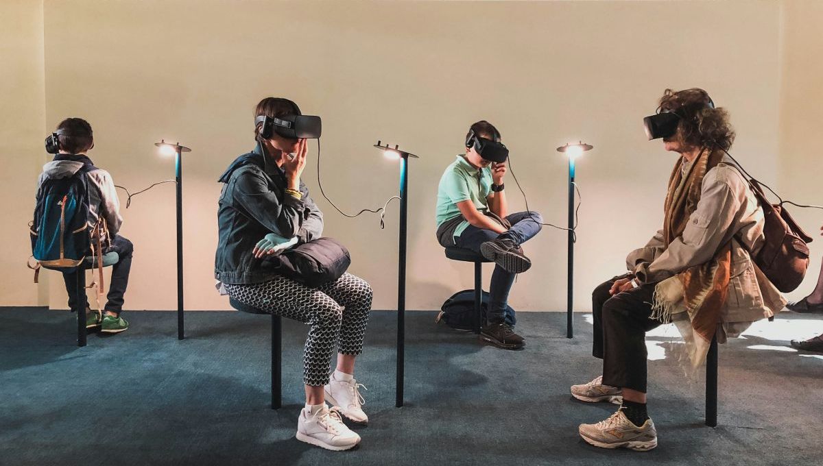Quatre personnes assisent portent un casque de réalité virtuelle dans ce qui semble être un musée.