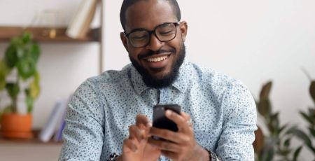 Happy african american businessman using phone mobile apps at workplace