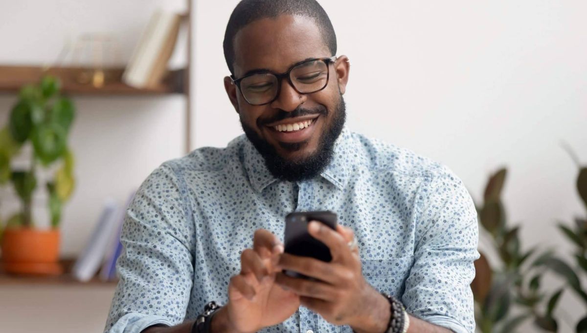 Happy african american businessman using phone mobile apps at workplace