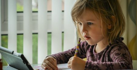Une petite fille fait ses devoirs avec une tablette