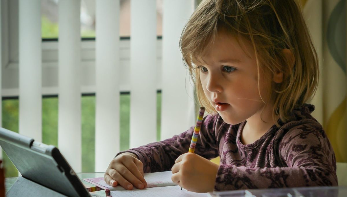 Une petite fille fait ses devoirs avec une tablette