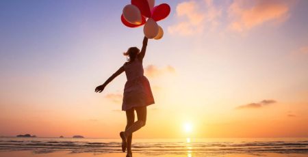 imagination, happy girl jumping with multicolored balloons at sunset on the beach, fly, follow your dream