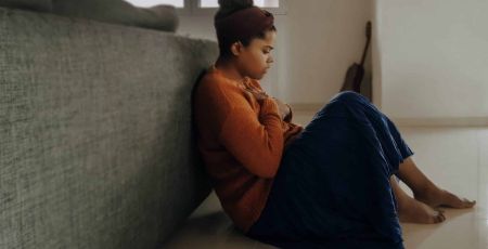 Une femme est parterre adossée à son canapé