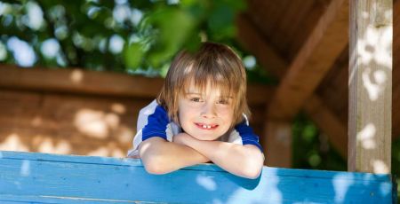 Enfant souriant dans une cabane dans les arbres - crédit photo : contrastwerkstatt via Adobe Stock