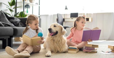 Deux petites filles lisent en présence d'un chien