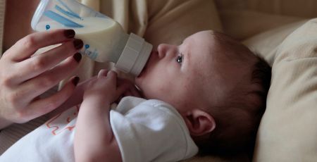 Un bébé boit au biberon du lait