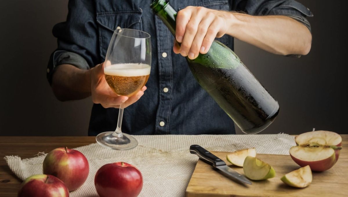 Male hands pouring premium cidre in wine glass above rustic wood table. Tasting vintage apple cider out of ice cold bottle