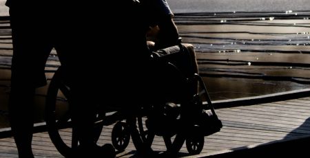 Homme assis sur un fauteuil roulant avec un autre qui le pousse