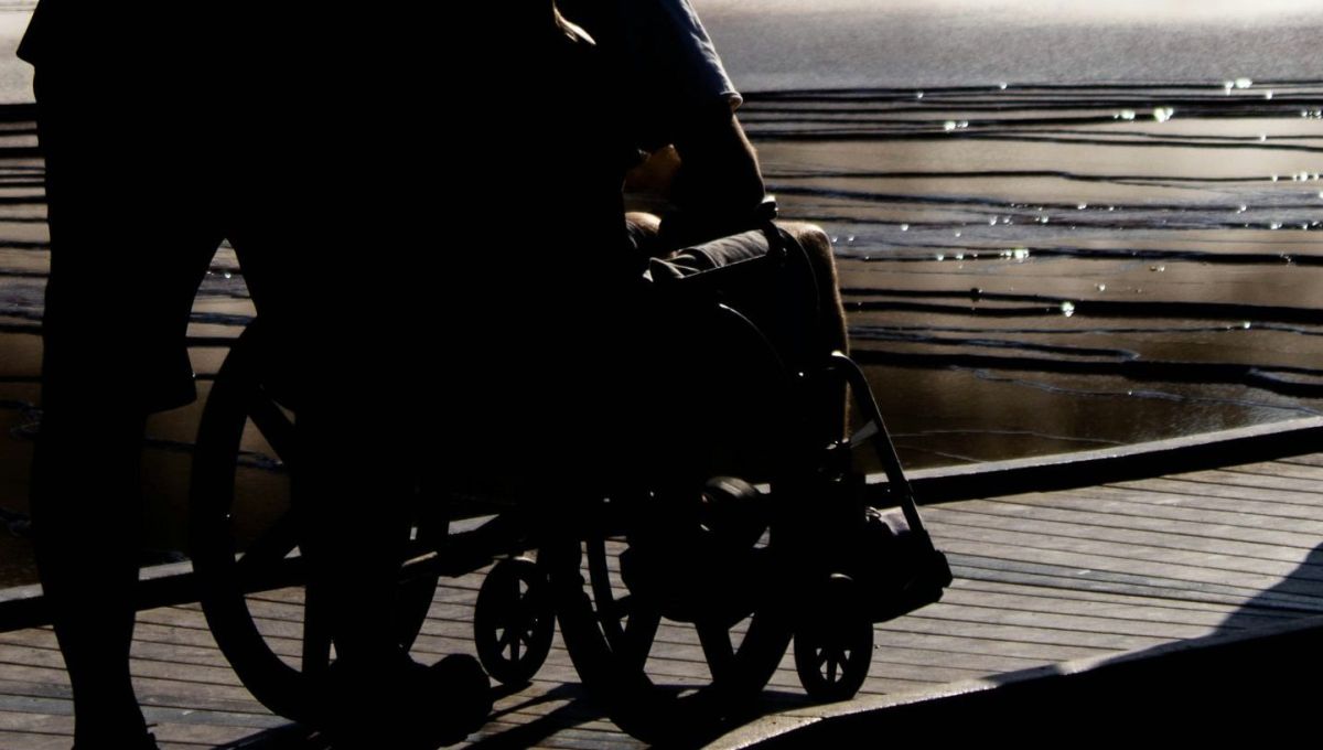 Homme assis sur un fauteuil roulant avec un autre qui le pousse