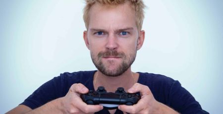 un homme tient une manette de jeux vidéos