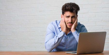 Un homme se bouche les oreilles, importuné par les bruits environnants.
