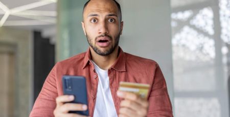 homme surpris au telephone avec sa carte bancaire