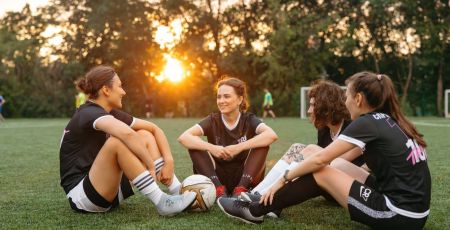 Femmes assises sur l'herbe avec un ballon de football